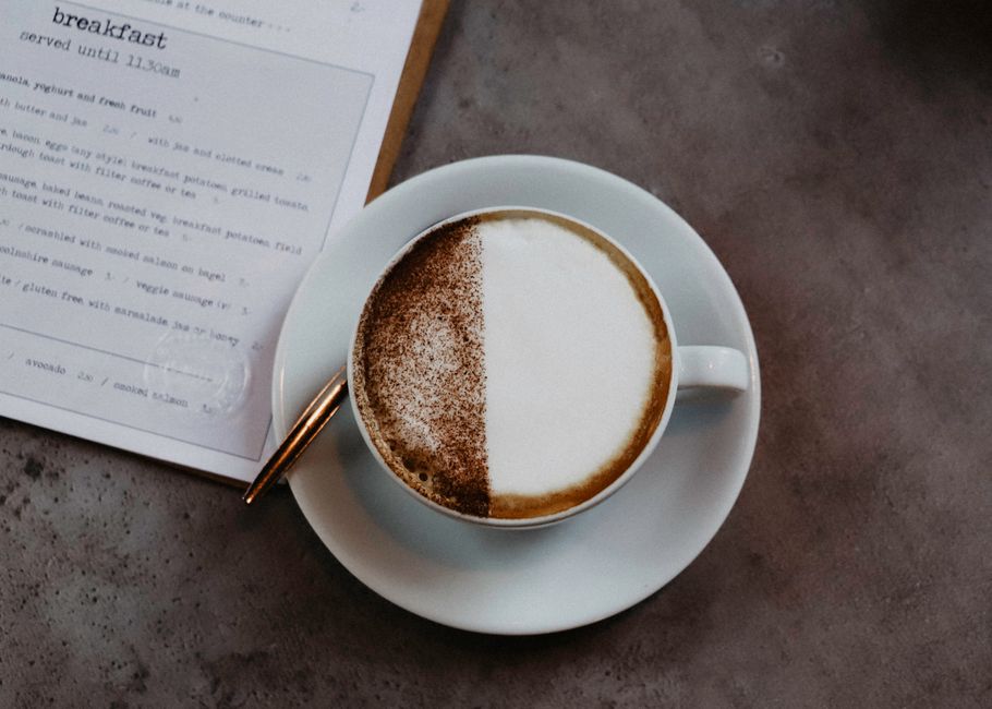 Elegant top view of a cappuccino with latte art beside a breakfast menu on a table.