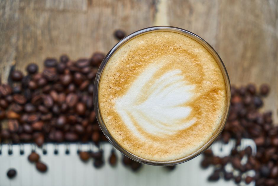 Top view of a latte with beautiful latte art and coffee beans, perfect for coffee enthusiasts.