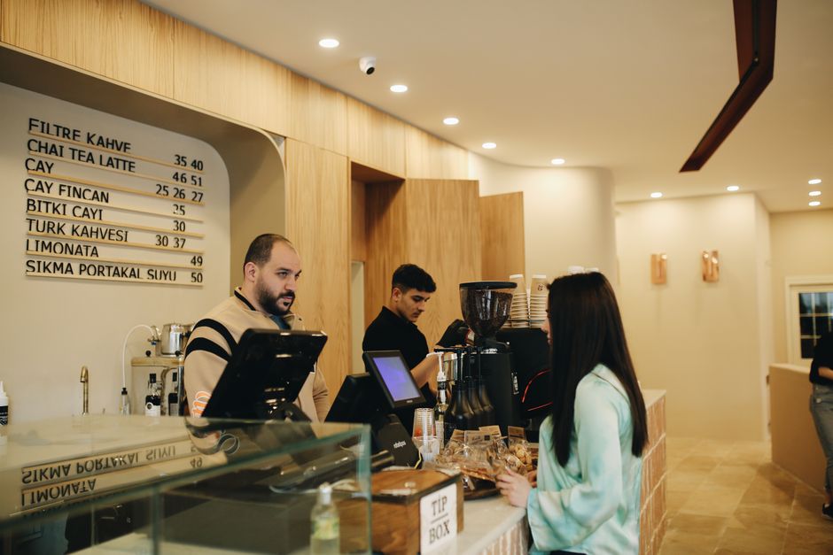 A modern café interior showing baristas preparing coffee and customers at the counter.